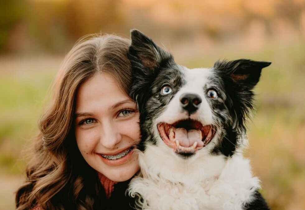 A woman beams with joy as she lovingly holds her dog in her arms